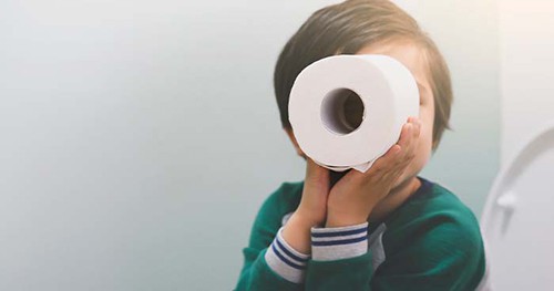 Image: a child playing with a full roll of toilet paper.
